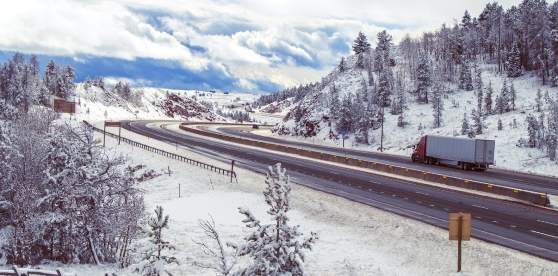 semi truck driving up mountain road in winter
