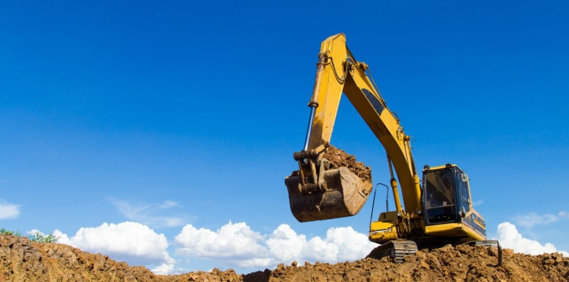 large excavator scooping dirt with blue sky background