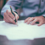 man's hands signing paperwork
